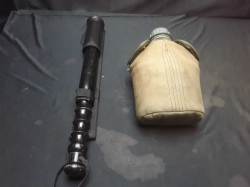 An ebonised wooden truncheon with a black leather belt hanger & militrry water bottle in sleeves & belt holder