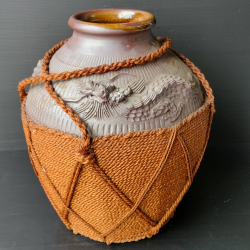 A vintage chinese terracotta jar with woven rope jute protective covering with dragon on the sides (H.30 cm. Dia. 30 cm.)