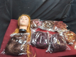 A box of ladies artificial hair wigs and a hairdressing practice head