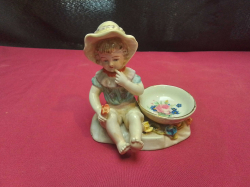 An antique German hard paste porcelain child figure with small ring dish marked underneath 12cm high x 10cm wide