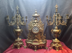 A Solid bronze 8 day clock with ceramic face and 2 brass garnatures Candlesticks with stand. Approx. 62x36x10 cm