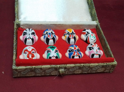 A set of 8 Miniture Japanese face masks complete in original box 8x13 Cm.