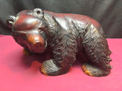 A massive hand carved wooden bear signed on paws. L.32 H.16 Cm.