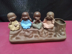 A Chinese pen holder with 4 sat children mimicking the 3 wise monkeys.L.22 H.9 Cm.
