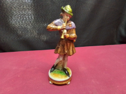 A Rudolf Kamer Figure (marked to base) of a Boy Playing a Trumpet. W.6.5 H.18.5 Cm.