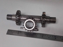 An artistic piece constructed from mechanical parts, resembling a shaft with gears.