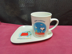 A Snoopy cup with tray has place for cup to sit on 