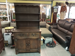 A dark oak Welsh dresser features a two-section design with a lower base cupboard and an upper plate rack display. W.91 D.43 H.175 Cm.