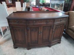 A dark brown wooden Old Charm oak sideboard Buffet features intricate carvings and a curved front design. D.58 L.140 H.92 Cm.