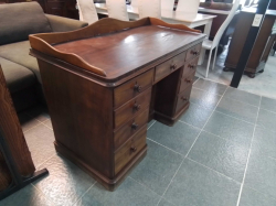 An antique 19th-century mahogany pedestal desk features a distinctive gallery back and nine drawers with original wooden knob handles. D.62 W.124 H.88 Cm.