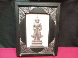 decorative wall hanging features a Thai amulet depicting Thao Wessuwan (a Buddhist guardian giant) set in a dark wood frame with detailed silver-colored corner accents. W.25 H.32 Cm.