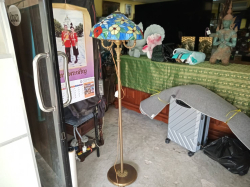 A Tiffany floor lamp features a floral stained glass shade and a patinated bronze base. W.32 H.157 Cm.