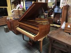Over string baby grand piano, a high quality instrument in walnut  in a good condition. W.125 D.130 H.160 Cm.