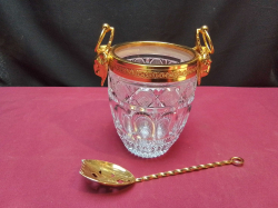 A vintage French ice bucket features gilded metal ram head handles and a detailed crystal body W.15 H.15 Cm. with large spoon.