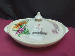 A decorative ceramic oval covered casserole dish featuring a vibrant floral design of orange and purple flowers.L.31 W.19 H.18 Cm.