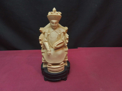 A vintage Chinese carved emperor figure, likely made of resin or bone, seated on a throne with stamped to base. W.9 H.18 Cm.