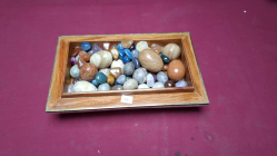 A large collection of stone eggs and other stone items in a Maitland Smith tessellated marble box 