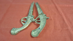 A Pair of brass wall hanging Pistols. W.34 cm