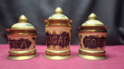 A Brass sugar canister featuring an ornate enamel label and a matching domed lid.