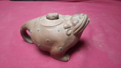 A Brown ceramic teapot shaped like a crouching toad