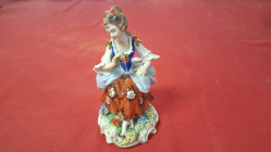 An antique Sitzendorf figurine of lady seated with flower in hand c1893-1923 