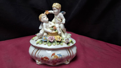 A vintage Meissen style lidded porcelain trinket box with cherubs and flowers 17cm wide x 19cm high in perfect condition