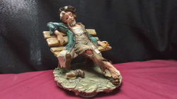 A Signed Capodimonte ceramic of a tramp on a bench.
H20 W18cm.