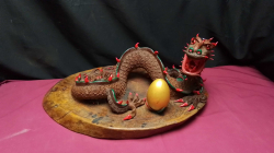  A massive hand carved sculpture of a mythical chinese dragon with a golden egg nestled inside the coiled body of the figure displayed on a wooden platter.
L40 W19cm.