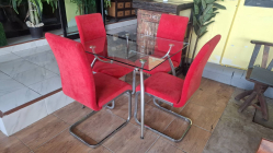 A Modern set rectangular glass top table with four red velvet chairs on metal frames. Dimensions table, 90x90 cm 75 cm high