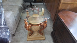 Decorative occasional center table with four carved praying figures with glass top